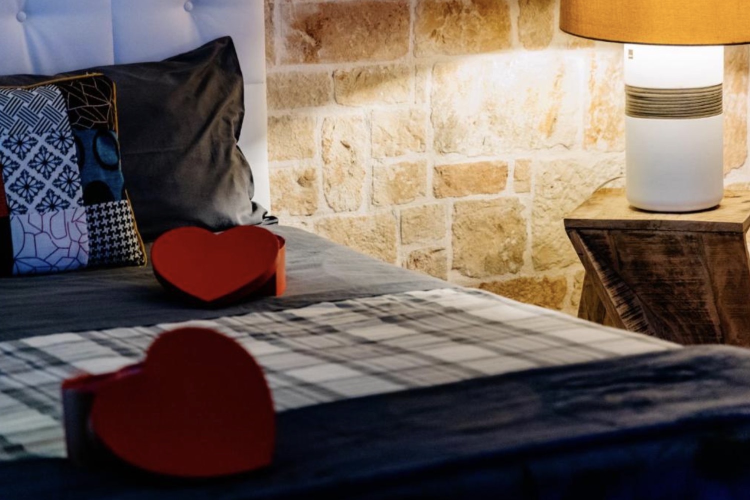 Dettaglio del letto, con cuori e parete in pietra pugliese