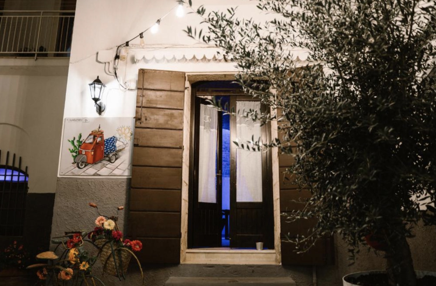 L'ingresso della struttura di sera, con la porta in legno e l'ulivo